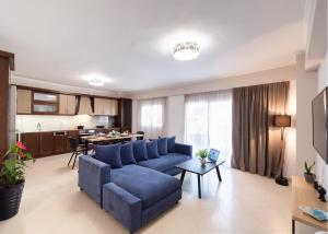a living room with a blue couch and a kitchen at Peratzada apartments in Vasiliki