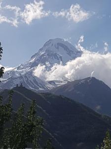 una montagna innevata con nuvole sullo sfondo di Cozy House Kazbegi a Kazbegi
