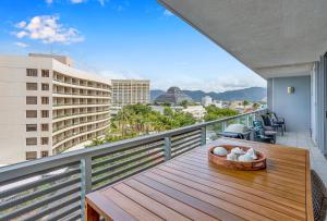 een balkon met een houten tafel en uitzicht op de stad bij Luxury 1BR Apartment @ Harbour Lights Cairns in Cairns
