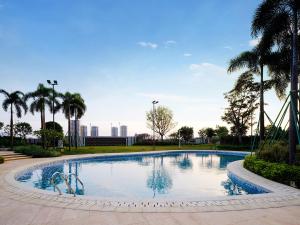 a swimming pool with palm trees in a park at White Swan VYV Hotel, Foshan in Foshan