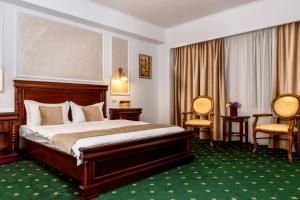ピテシュティにあるHotel Victoriaのベッド1台と椅子2脚が備わるホテルルームです。