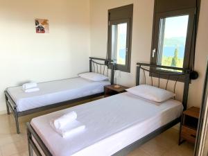 two beds in a room with two windows at ArtView Villa in Syvota