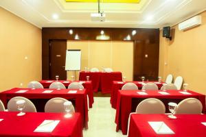 une salle de conférence avec des tables rouges et des chaises blanches dans l'établissement Favor Hotel Makassar City Center By LIFE, à Makassar