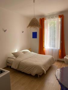 sypialnia z łóżkiem i oknem z pomarańczowymi zasłonami w obiekcie Studio neuf et lumineux - Ajaccio centre - Place Miot/Albert 1er w Ajaccio