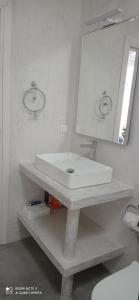 Baño blanco con lavabo y espejo en Maison de village vue mer, en Skhinokápsala