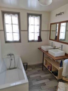 a bathroom with two sinks and a tub and two mirrors at Le Petit Poucet Appartement rez-de-chaussée avec grand jardin in Morzine +17 photos