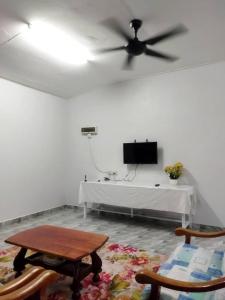 ein Wohnzimmer mit einem Deckenventilator und einem Tisch in der Unterkunft Homestay Abi in Kota Bharu
