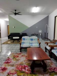 ein Wohnzimmer mit 2 Stühlen und einem Tisch in der Unterkunft Homestay Abi in Kota Bharu