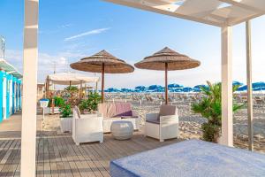 un patio con sillas y sombrillas en la playa en Hotel Cola Frontemare, en Bellaria-Igea Marina