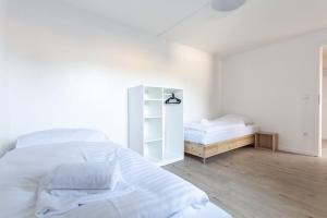 um quarto branco com uma cama e um espelho em T&K Apartments Wegberg 5 Monteur Apartments em Wegberg