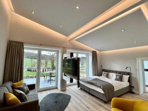 um quarto com uma cama, uma televisão e um sofá em DRIEHOF LandGut & Residenz LifeStyle-Comfort Apt 7 em Tecklenburg