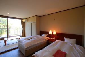 two beds in a hotel room with a window at hokkein-onsen kougen-terrace in Kokonoe