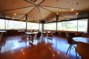 a dining room with tables and chairs and windows at hokkein-onsen kougen-terrace in Kokonoe