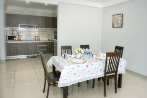 einen Esstisch mit Stühlen und einem Tisch sowie eine Küche in der Unterkunft Borneo Peak - Marina Court Seaview Condominium in Kota Kinabalu