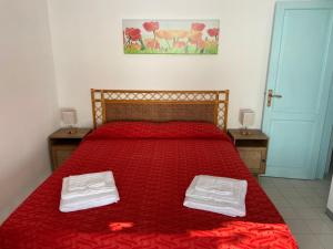 a bedroom with a red bed with two white towels on it at House sole - Unique Panorama in Lipari