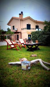 dwa krzesła i stół w trawie przed domem w obiekcie A casa d'Irene w mieście Mantzavináta