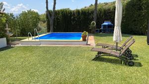 einen Stuhl und einen Regenschirm neben einem Pool in der Unterkunft Casa Rural Cupiana Piscina privada Malaga in Málaga
