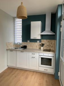 a kitchen with white cabinets and a green wall at LE NID SUR LA FALAISE in Ault