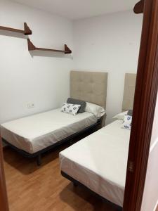 two beds in a room with white walls and wood floors at Vivienda Fines Turísticos La Victoria in Jaén