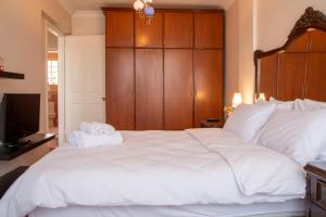 a bedroom with a large white bed with a wooden headboard at Spacious Detached House with Garden in Izmir in Ulucak