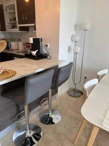 uma cozinha com um balcão com cadeiras e um balcão em Penthouse familial avec vue mer em Manilva