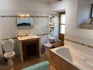 a bathroom with a tub and a toilet and a sink at Les chambres de la Bastide in Saint-Sauveur-de-Montagut