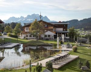 a lodge with a pond in front of a building at Hotel Chalets Grosslehen in Fieberbrunn