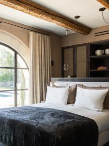 - une chambre avec un grand lit et une grande fenêtre dans l'établissement Terres Rouges, à Maussane-les-Alpilles