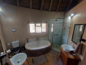 a bathroom with a tub and two sinks and a shower at Izintaba Private Game Reserve Waterberg in Vaalwater