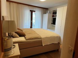 a bedroom with a bed and a table with a lamp at 2.5 Zimmer Wohnung Davos Platz in Bolgen