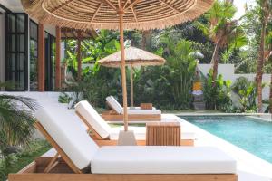 an outdoor patio with chairs and an umbrella and a swimming pool at Villa Lestari Ubud in Tegalalang