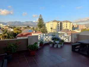 a balcony with potted plants and a table and buildings at Royal Classico Getaway in Strand Beach in Cape Town