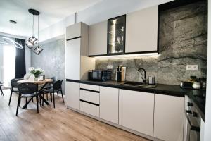 a kitchen with white cabinets and a table with chairs at Just 5 by Housine in Zator