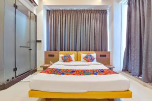a bedroom with a large bed with colorful pillows at FabHotel Gold Palace Inn in Surat