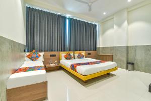 a bedroom with two beds and a window at FabHotel Gold Palace Inn in Surat