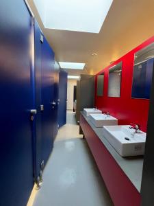 Baño con 3 lavabos y paredes rojas y azules en The Old Factory, en Copenhague
