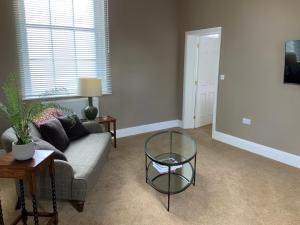 a living room with a couch and a glass table at The Mulberry Apartment at Langford Hall in Newark upon Trent