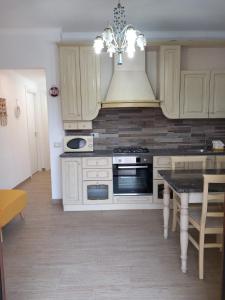 a kitchen with white cabinets and a stove and a table at Casa vacanze M&M Tortolì in Tortolì