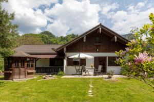 a house with a table and an umbrella in the yard at Ganzes Haus mit großem Garten und eigener Sauna in Unterwössen