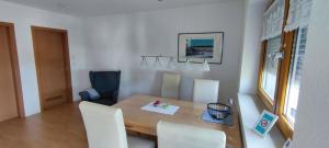 ein Esszimmer mit einem Holztisch und weißen Stühlen in der Unterkunft FeWo Lindlar, Monteurwohnung in Lindlar