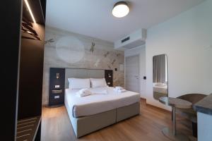 Un dormitorio con una gran cama blanca y una mesa en Hotel Arilica en Peschiera del Garda