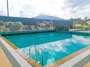 a swimming pool with blue water and rocks at The Dome @ Gua Musang in Gua Musang