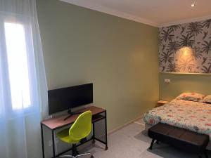 een slaapkamer met een bed en een bureau met een televisie bij Maison au bord de l'eau et au calme pour les vacances in Saint-Denis-de-Pile