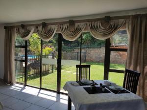 a dining room with a table and a large window at El Shadai Guest House & Spa Hartbeespoort in Hartbeespoort