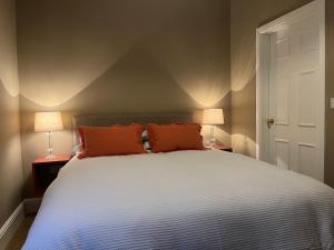 ein Schlafzimmer mit einem Bett mit orangefarbenen Kissen und zwei Lampen in der Unterkunft The Mulberry Apartment at Langford Hall in Newark upon Trent