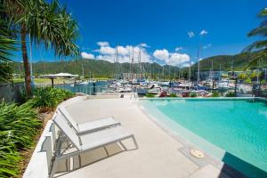 a swimming pool next to a marina with boats at Blue on Blue Superior Studio Room 1221 in Nelly Bay