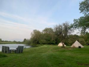 dos tiendas de campaña y una mesa y sillas junto a un lago en Camping By The River 