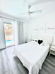 Un dormitorio blanco con una cama y un ventilador de techo. en CHALET 273 con PISCINA PRIVADA, en Callao Salvaje