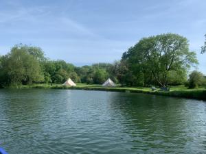 a view of a river with tents in the background at Camping By The River in Sutton Courtenay