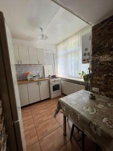 une cuisine avec des placards blancs et une table. dans l'établissement Apartamentul Oaspetilor, à Slatina